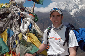 Lee stands next to prayer-flag adorned chorten.