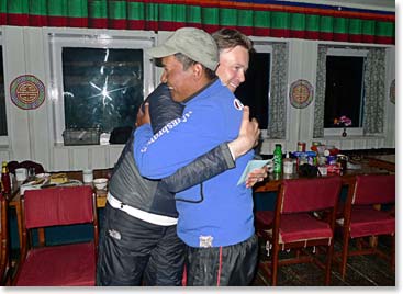 A climber and Sherpa guide share a warm hug after a successful summit.