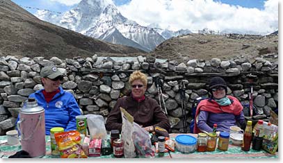 The girls huddle behind a wall out of the wind as they enjoy their lunch.