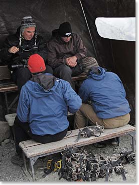 The team putting on their crampons, protected from the wind