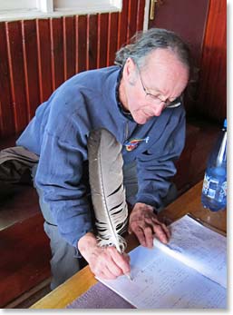 With an eagle feather pen, Reginald signs the guest book at Refugio Grey.