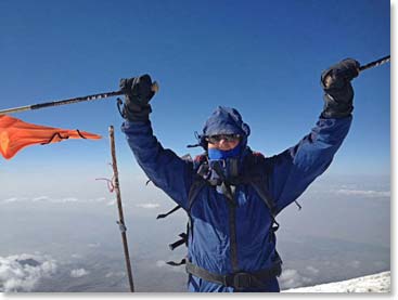 Peter Idenburg on the Summit. Moments before this photo was taken Peter’s impressive warm Russian hat was blown off his head in the strong summit winds. Peter feels that he has left his hat in an appropriate place and who knows, with wind like this maybe the hat will blow all the way back to Russia!