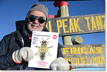 Frank Giustra holding his magazine on the summit of Kilimanjaro - Modern Farmer
