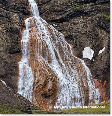Hiking at Raudofossar (means red waterfall), in the South-center of Iceland at the foot of Rauðufossafjöll. The river Rauðufossakvísl drops down over 60 meters and creates a bridal veil of water with a light red colored background. Rauðufossar means red waterfall.